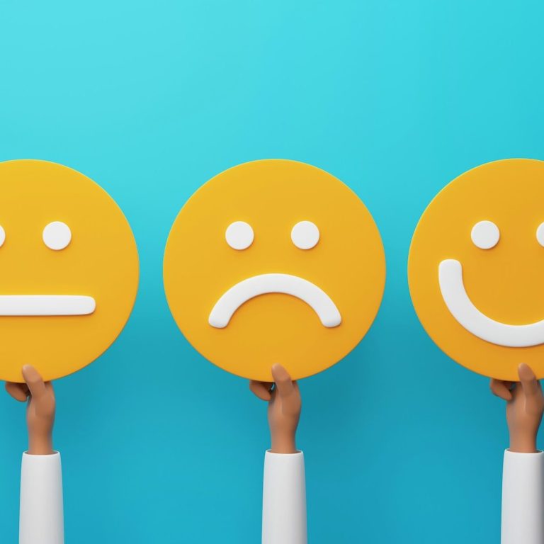 Drei gelbe Gesichtssymbole: neutral, traurig und lächelnd, vor blauem Hintergrund gehalten.