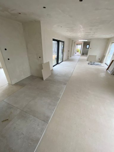 Blick in einen leeren Raum mit hellem Fußboden und unverputzten Wänden.