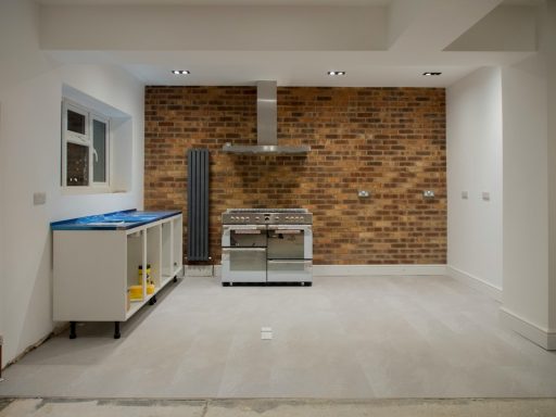 Bild von IONOS Moderne Küche mit Backsteinwand, Herd, Dunstabzug und unvollständigem Küchenschrank.