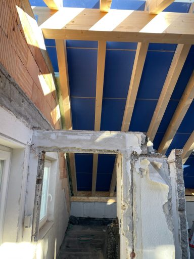 Dachkonstruktion mit blauen Platten und sichtbaren Holzträgern über einem offenen Raum.