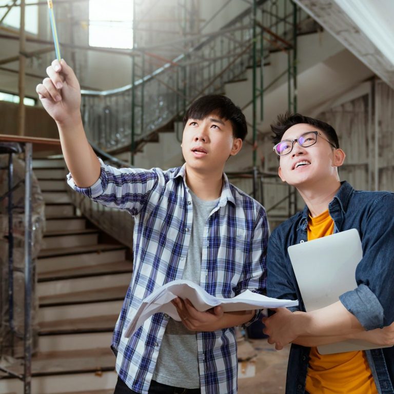 Bild von IONOS Zwei Männer besprechen Pläne in einem unvollendeten Bauprojekt.