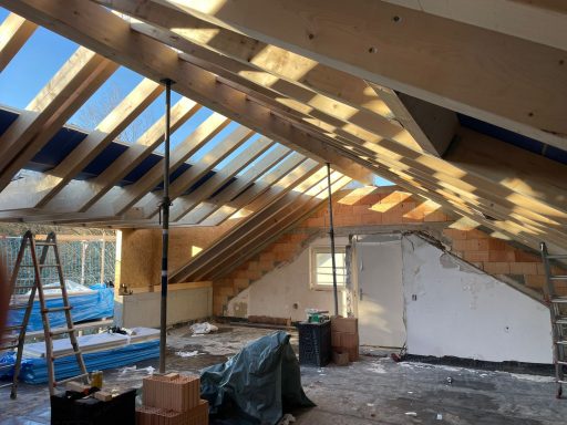 Unvollendeter Dachausbau mit Holzrahmen und Baustellenmaterialien.